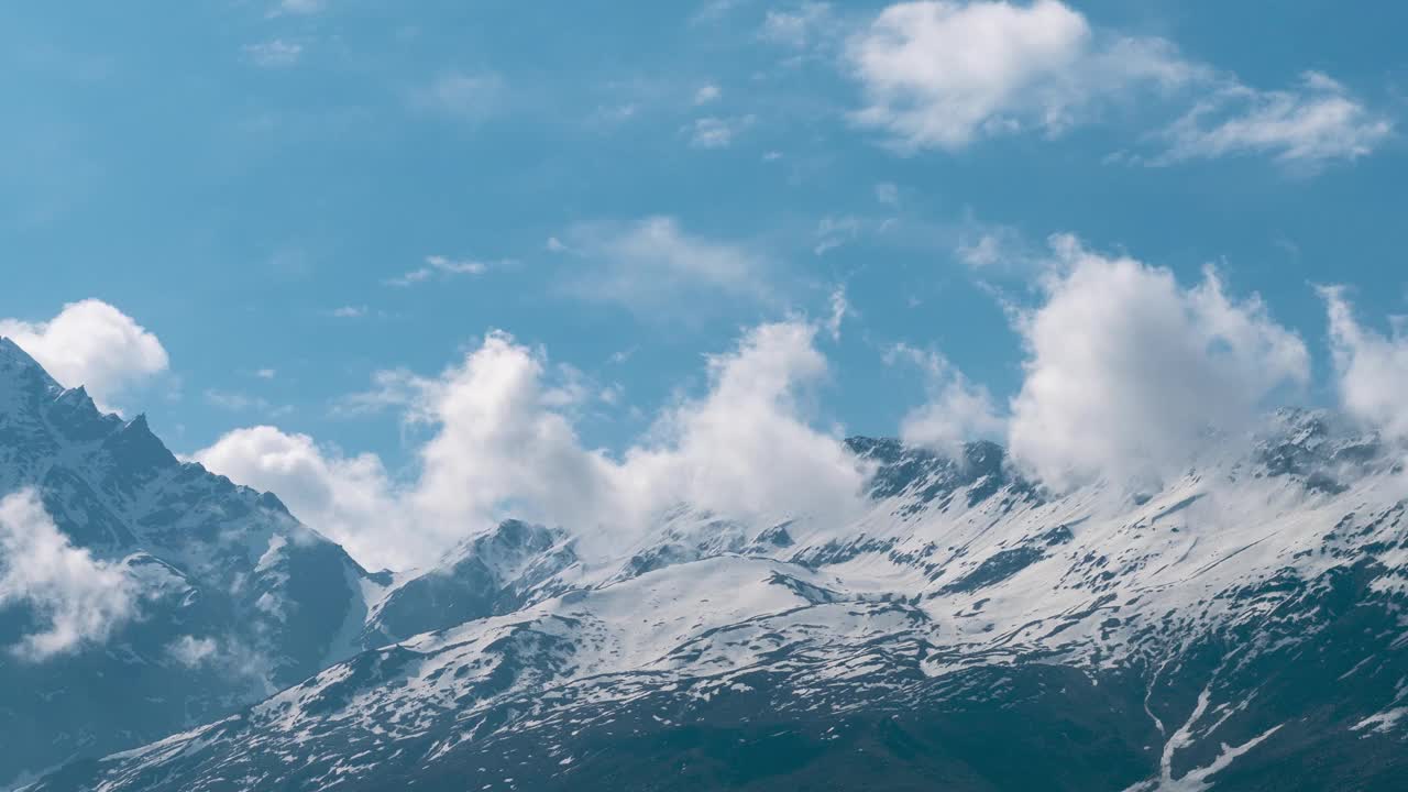 4K延时拍摄的柔软的白云在印度喜马偕尔邦拉胡尔的雪山上移动。山上的季风云。自然景观。史诗般的喜马拉雅山时间流逝。视频素材