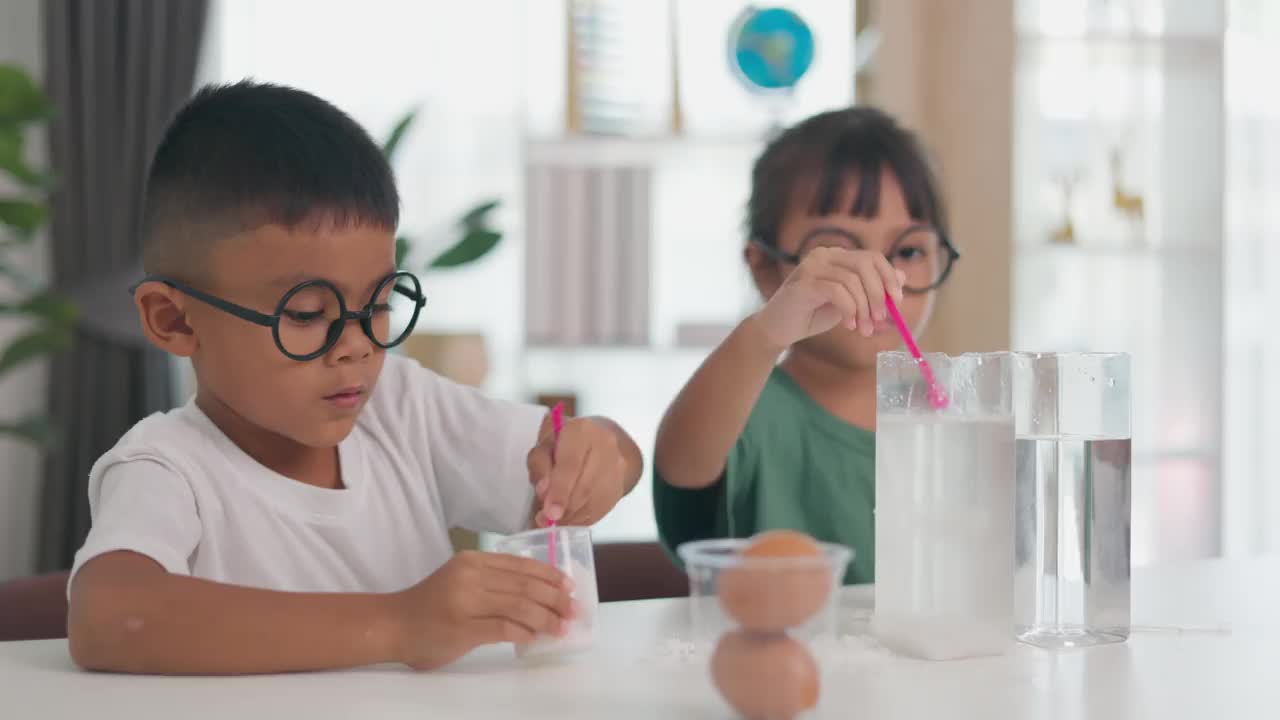 两个孩子在做关于鸡蛋下沉和漂浮的科学实验。视频下载