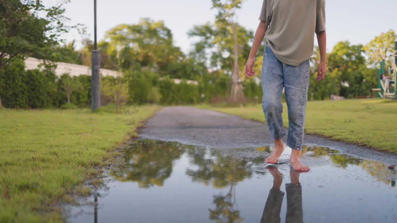 一个小女孩走在潮湿的人行道上。视频下载