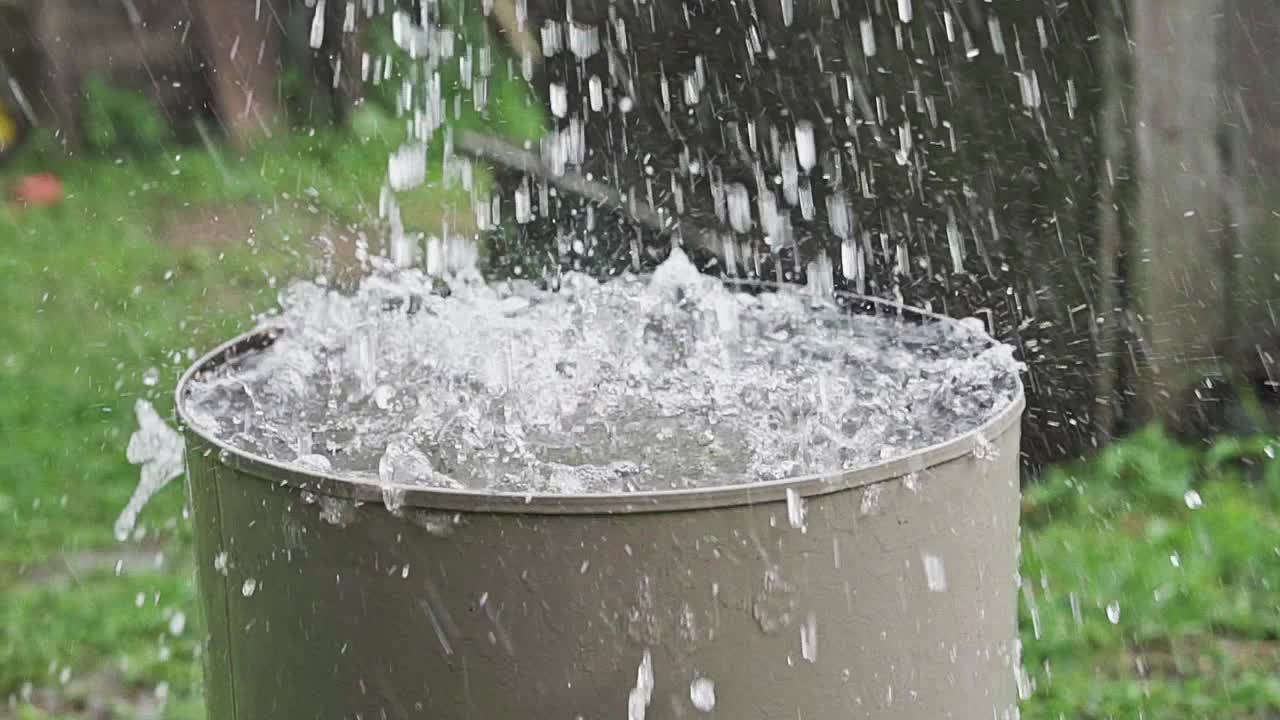 雨桶。大雨时，一股强劲的水流涌进一个旧金属桶视频素材