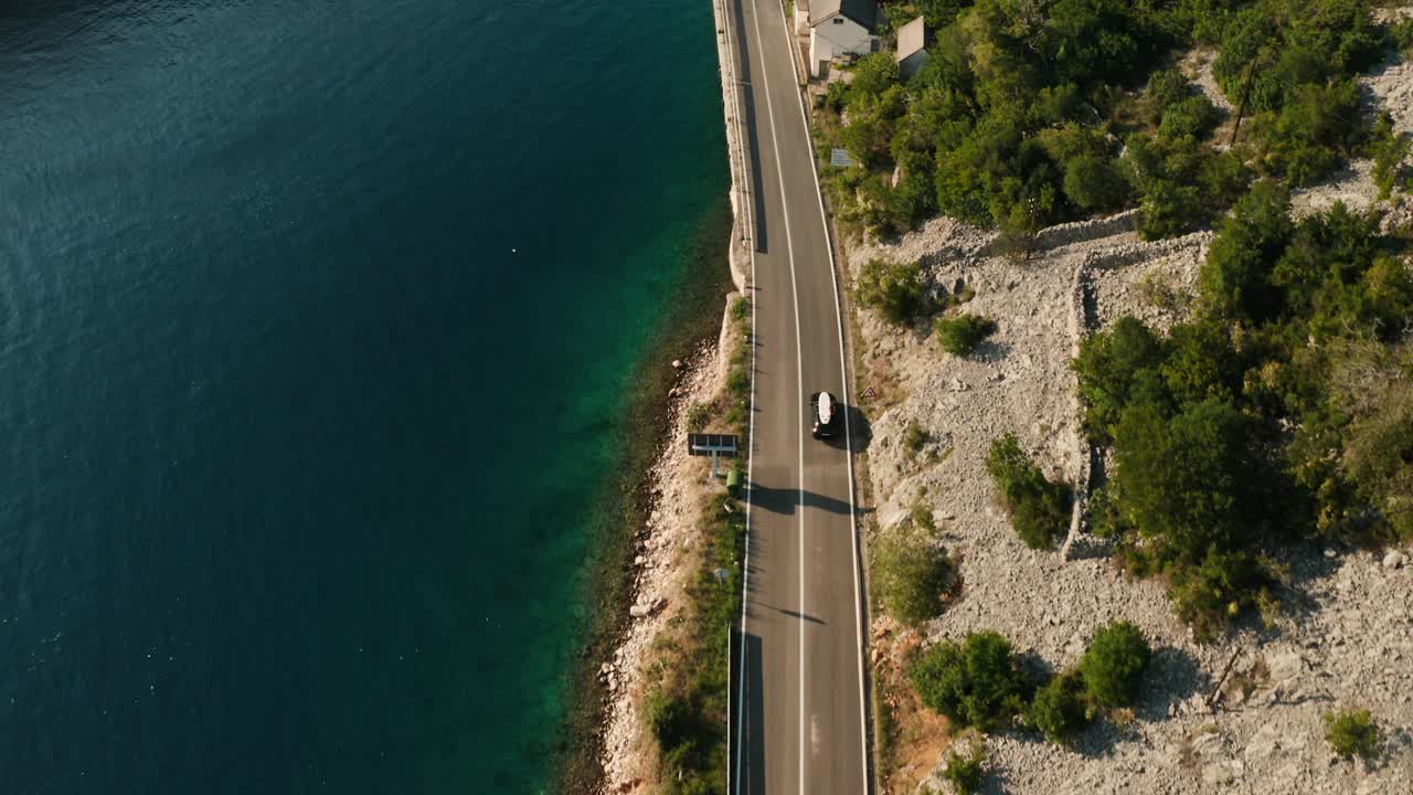 一辆车顶装有SUP的跑车沿着海岸公路疾驰而过。视频素材