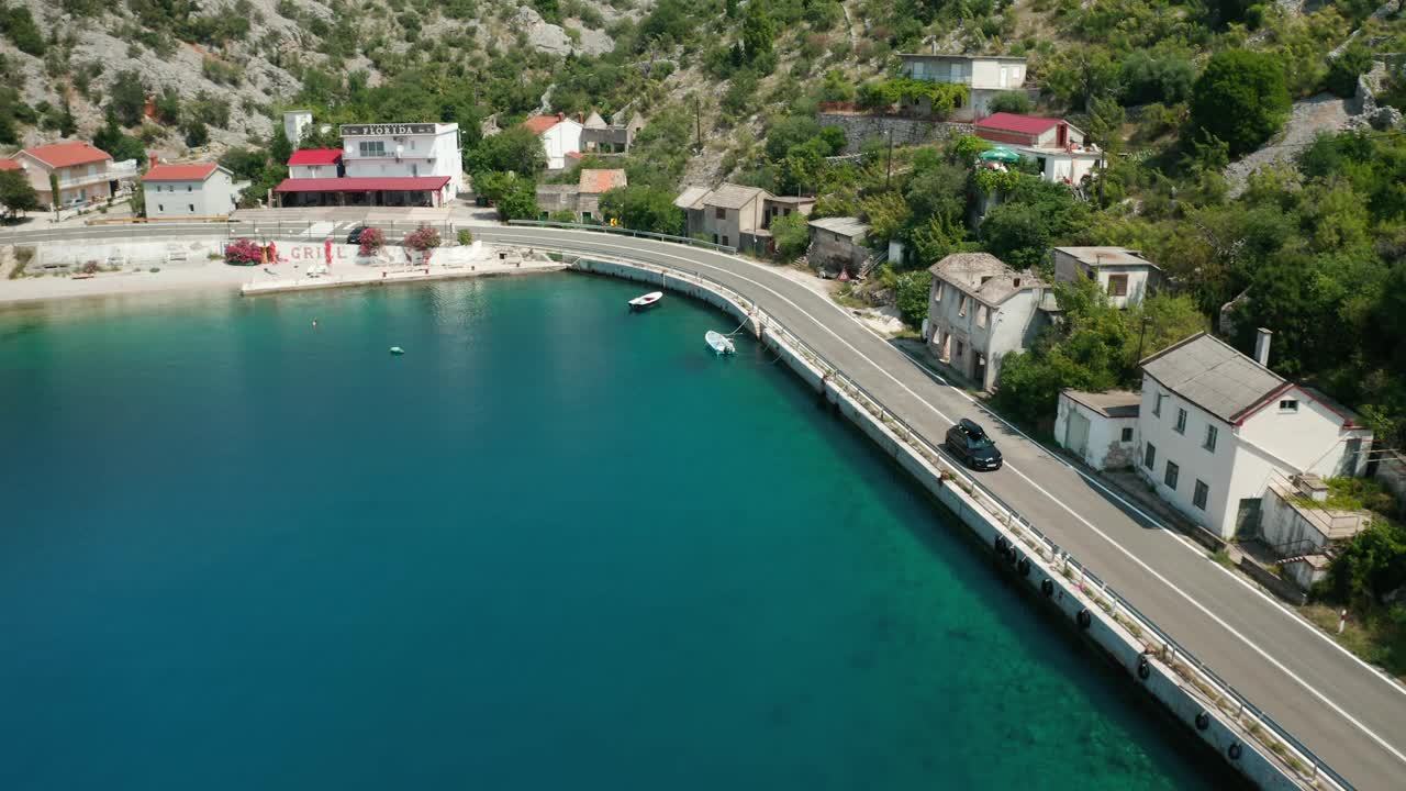 日出时，带顶棚的汽车沿着海岸公路行驶，一侧是多岩石的山坡。视频素材