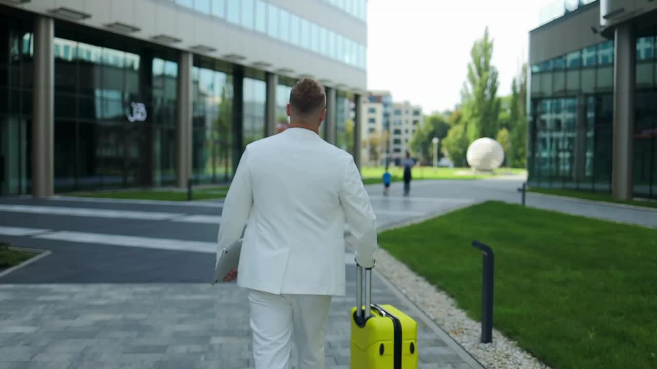 络腮胡子的商务旅行者用智能手机提着行李箱。拿着手机在机场候机楼等候的白人商人。视频下载