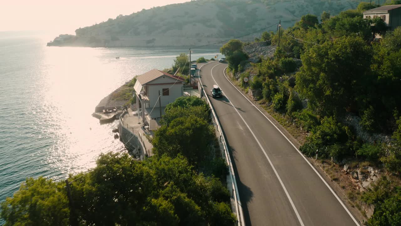 车顶装有桨板的汽车行驶在热闹的沿海道路上视频素材