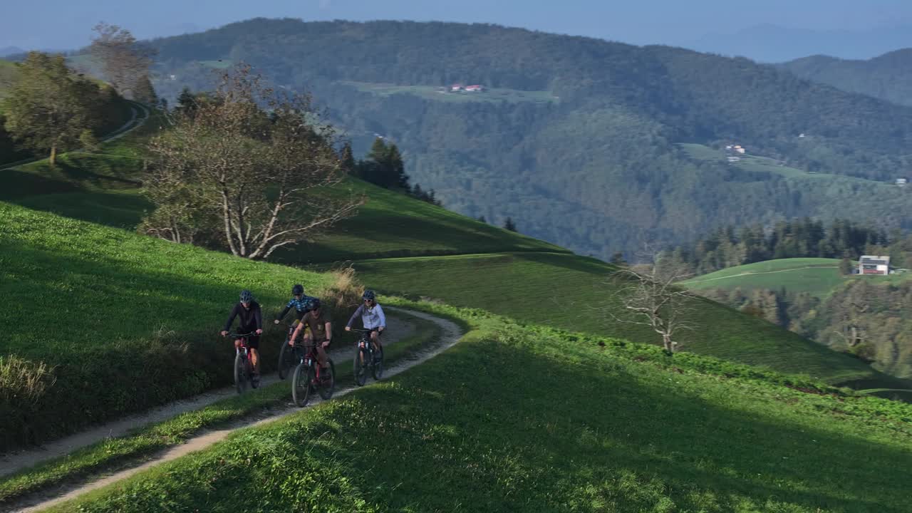 航拍:一群骑自行车的年轻人沿着风景如画的山间小道骑行视频素材