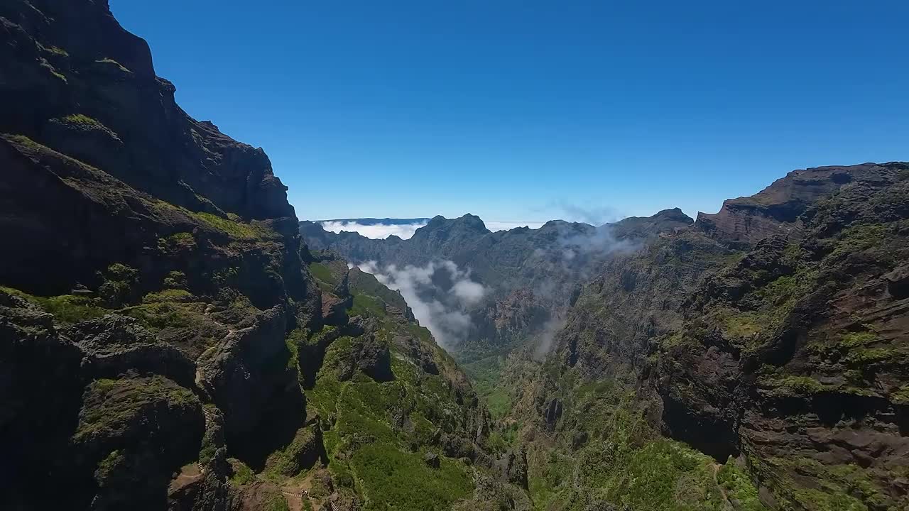 崎岖的地形和深谷在马德拉山脉，葡萄牙。沿着悬崖边缘的徒步小径。无人机的鸟瞰图，向前飞行。视频素材