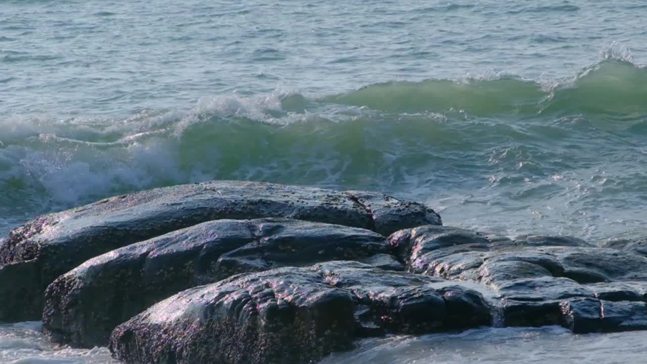 海浪在海岸上碾压石头的慢动作视频。视频素材