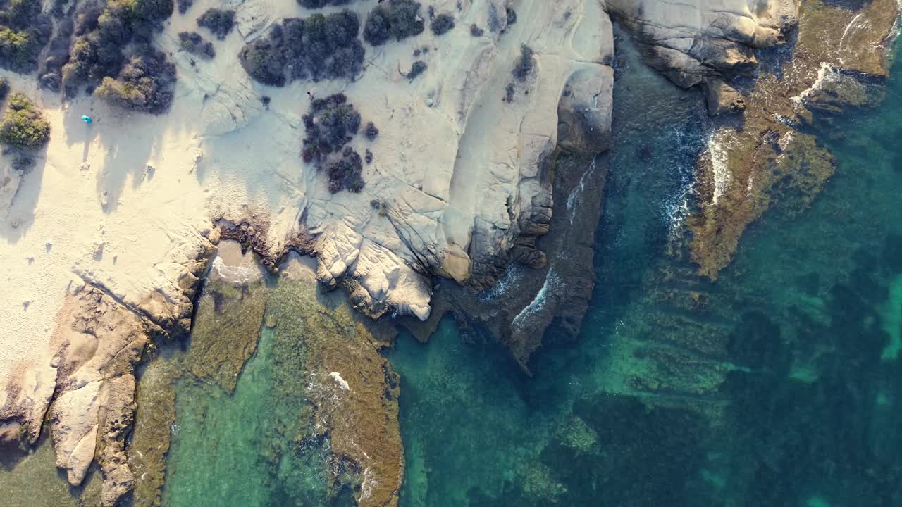 鸟瞰图，平静的水体旁边是多岩石的海岸线视频下载