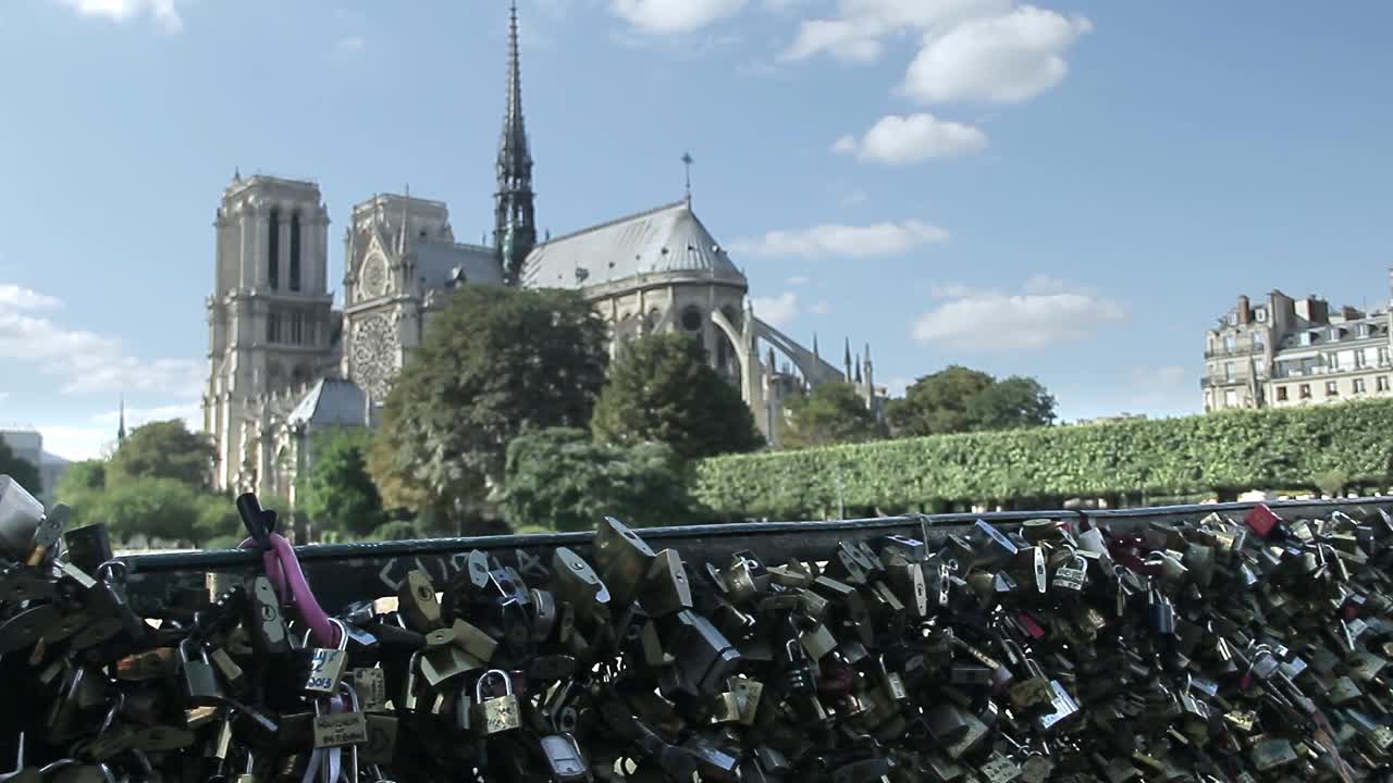 爱情的挂锁在桥的栏杆上'Archevêché，背景是巴黎圣母院。2015年8月，法国巴黎视频素材