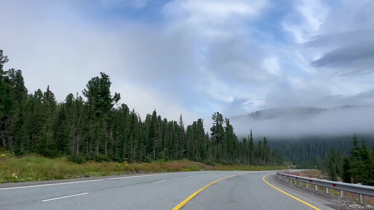 从道路的汽车窗口的视角。汽车沿着多云的森林景观行驶。旅行，旅行，开车旅行视频下载