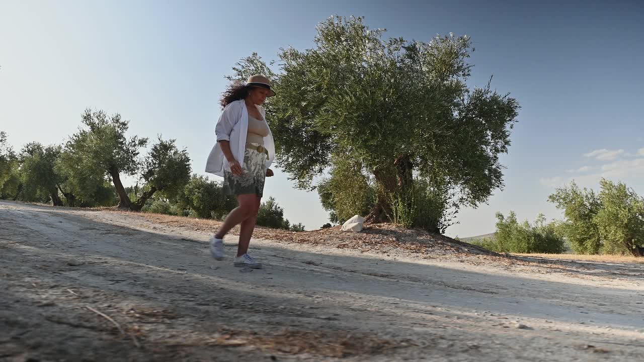 一个女人在阳光明媚的天空下漫步在大自然中，享受着户外的夏日视频素材