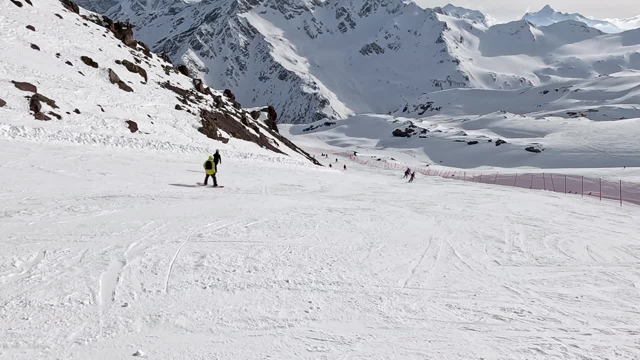 滑雪者和单板滑雪者在雪山斜坡上享受风景优美的下降视频下载