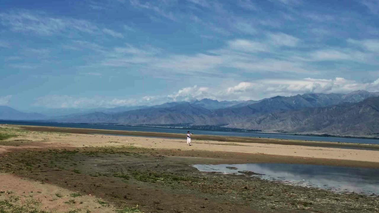 一名女游客正在山区湖岸拍摄视频视频素材