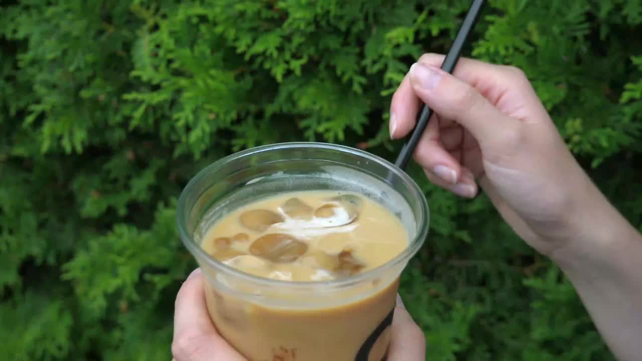 女性用手搅拌冰咖啡上的吸管，freddo cappuccino视频下载