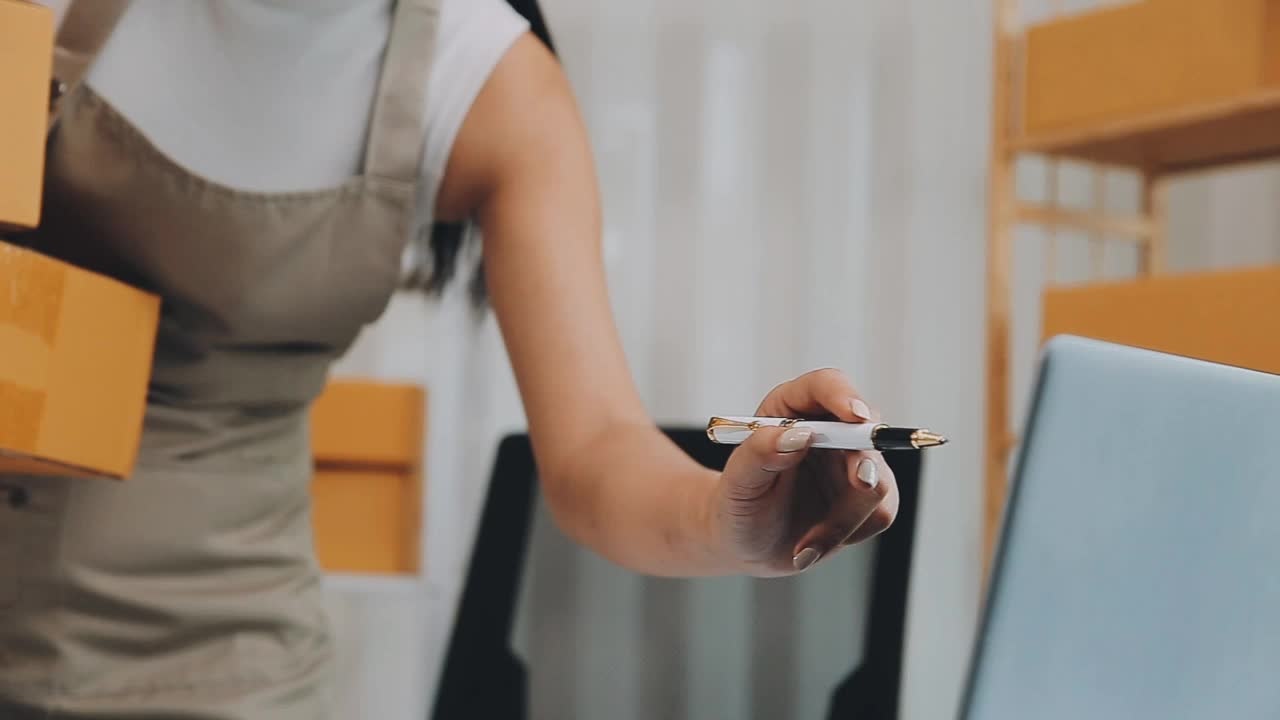 年轻的亚洲女性在家网上购物，联系顾客送货。视频素材