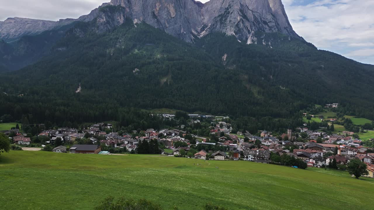 美丽的教堂坐落在绿色草地上的山谷中，背景是高山，白云石，意大利，欧洲，无人机视频素材