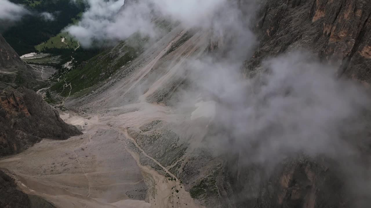 陡峭的岩石峡谷穿过一个山谷，有许多云和绿色的草地在背景，白云岩，意大利，欧洲，无人机视频素材