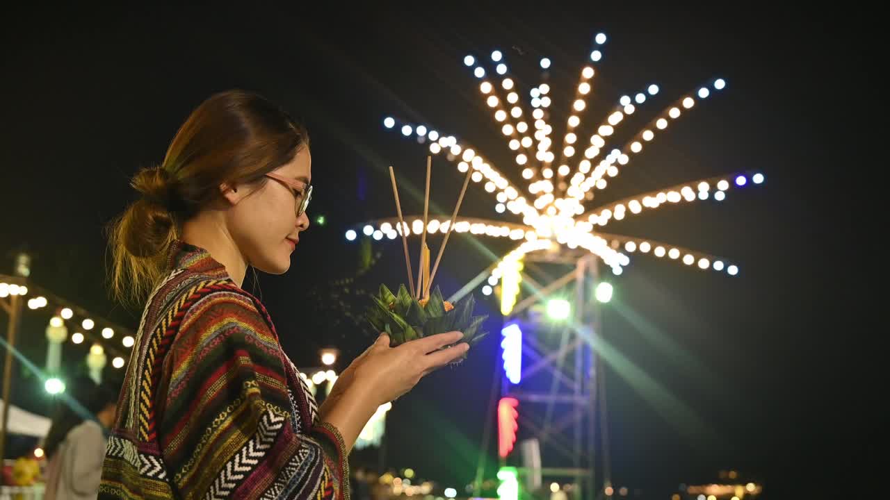 年轻的亚洲妇女拿着水龙包，在泰国的水龙包节上向水女神祈祷，然后把它放在水上。视频下载