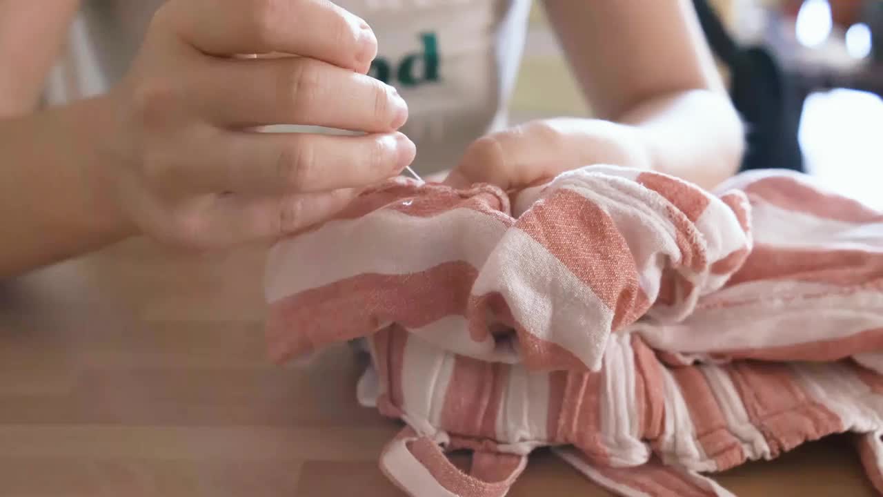 妇女用针和线把织物上的洞缝起来视频素材