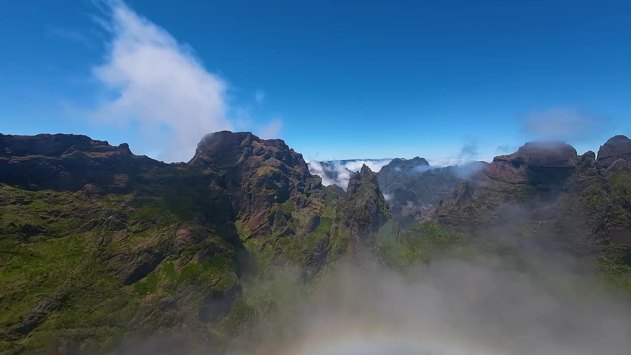 从空中俯瞰崎岖的山峰和云层之上的马德拉地貌。无人机观察岛屿地形和天空。视频素材