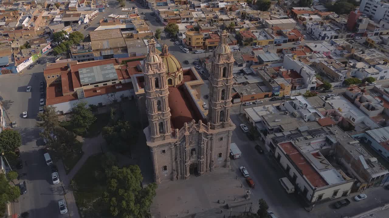 鸟瞰教堂Parroquia Basilica Santuario de Nuestra Señora de Guadalupe日落时的城市背景，美丽的宗教天主教建筑视频下载