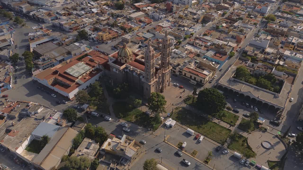 鸟瞰教堂Parroquia Basilica Santuario de Nuestra Señora de Guadalupe日落时的城市背景，美丽的宗教天主教建筑视频下载