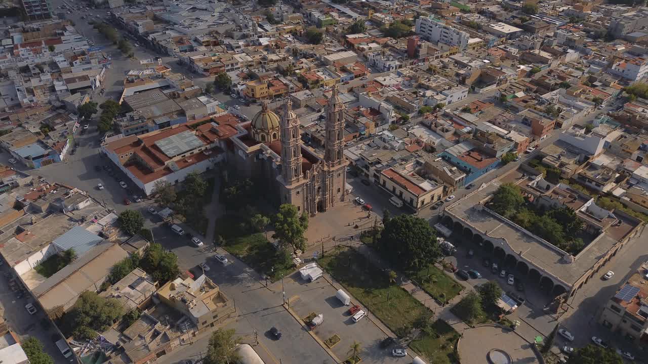 鸟瞰教堂Parroquia Basilica Santuario de Nuestra Señora de Guadalupe日落时的城市背景，美丽的宗教天主教建筑视频下载