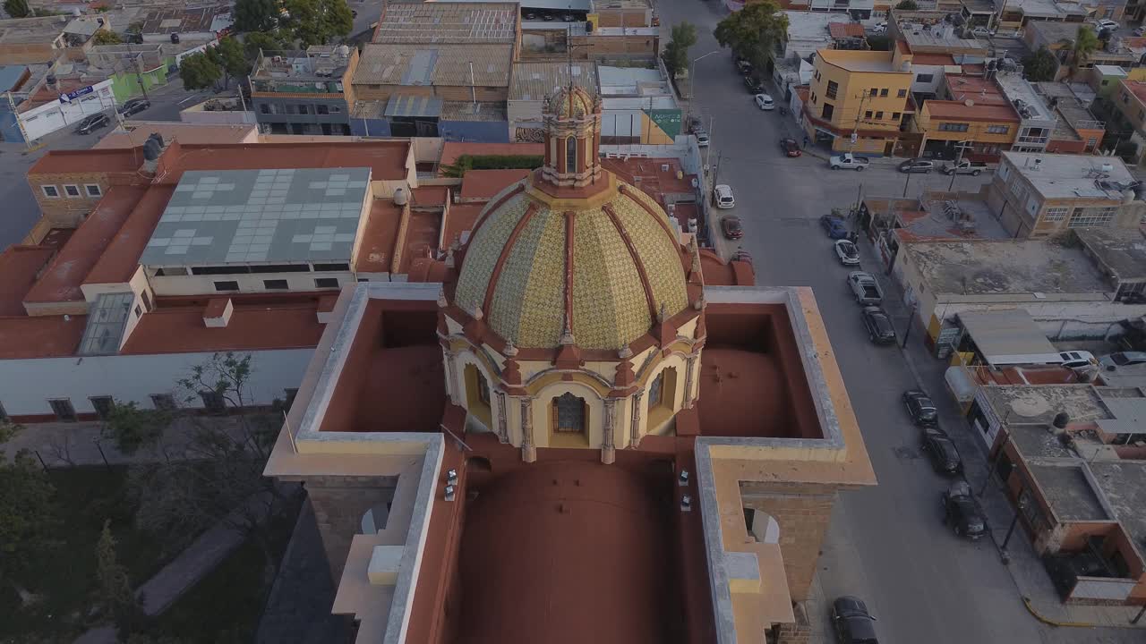 鸟瞰教堂Parroquia Basilica Santuario de Nuestra Señora de Guadalupe日落时的城市背景，美丽的宗教天主教建筑视频下载