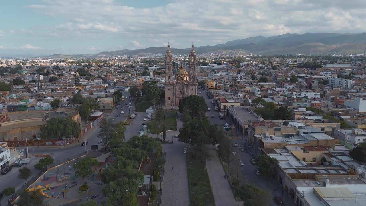 鸟瞰教堂Parroquia Basilica Santuario de Nuestra Señora de Guadalupe日落时的城市背景，美丽的宗教天主教建筑视频素材