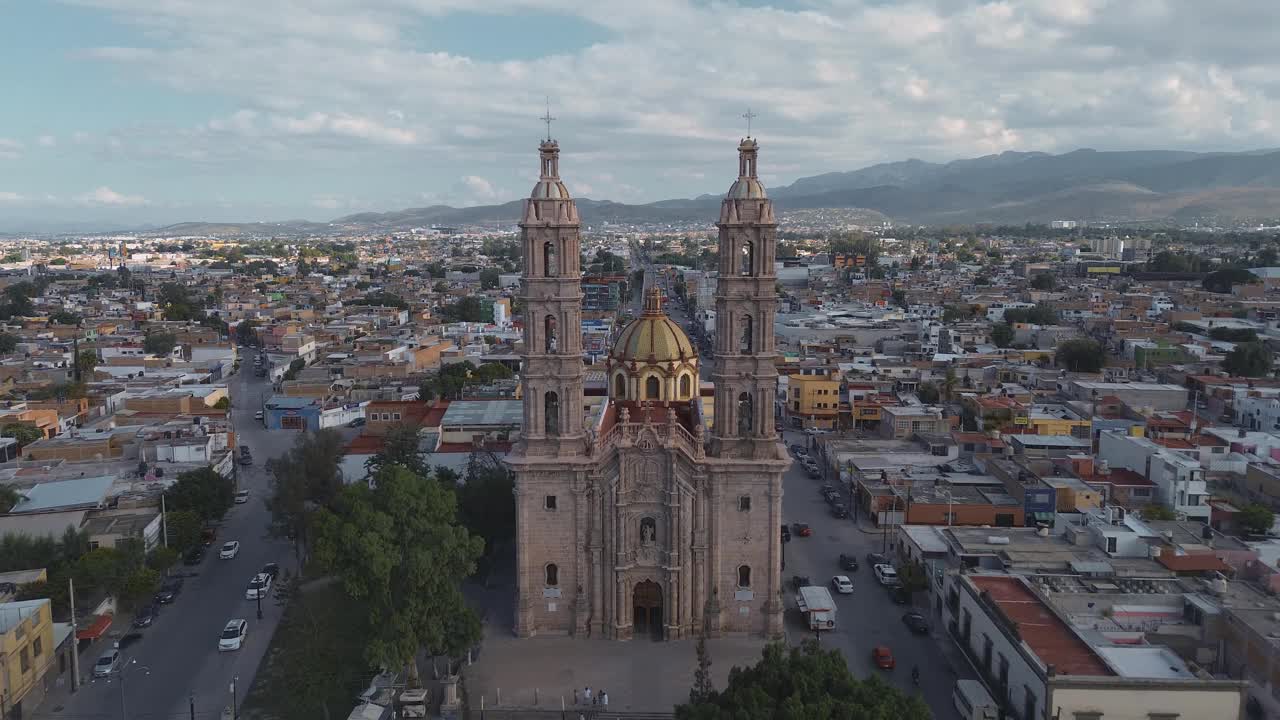 鸟瞰教堂Parroquia Basilica Santuario de Nuestra Señora de Guadalupe日落时的城市背景，美丽的宗教天主教建筑视频素材