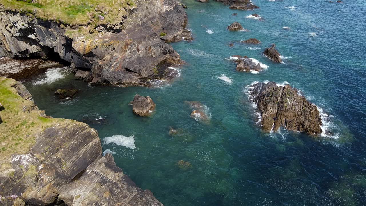 海浪轻柔地抚摸着崎岖的悬崖，阳光在宁静的水面上舞蹈，创造了一个宁静的海岸场景。视频素材