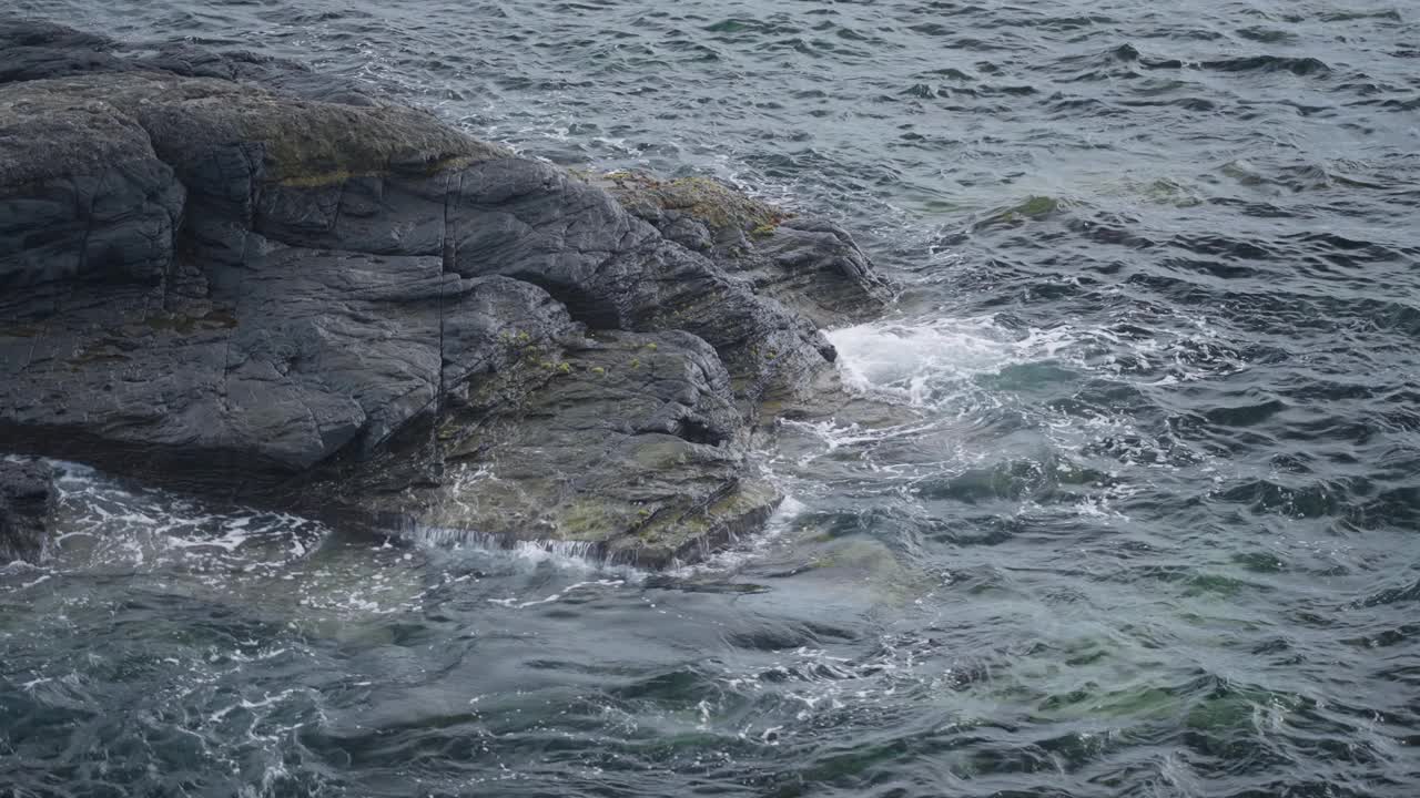 风平浪静的海边，海浪冲击着崎岖的岩石视频素材