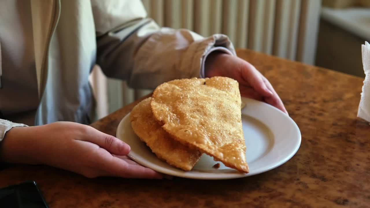 一个男人的手拿着一盘油炸肉饼。视频下载