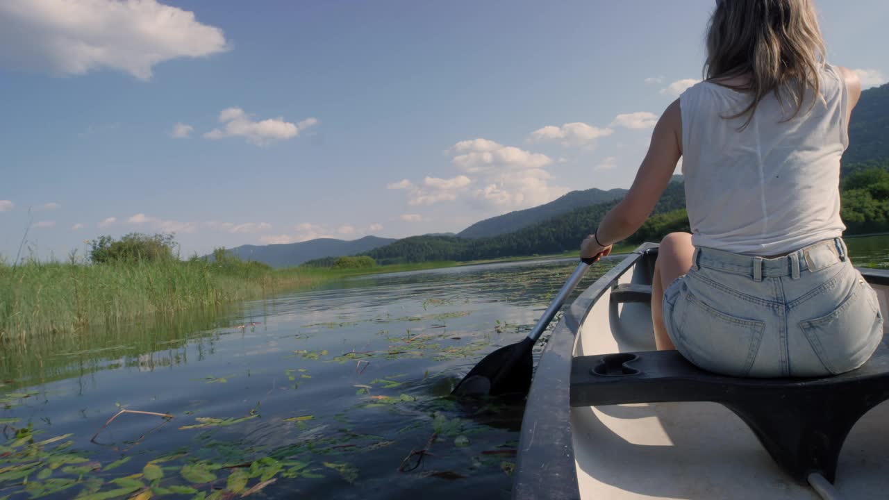 夏日里，一名女子在风景优美的湖面上划独木舟视频素材