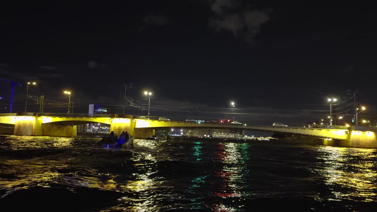 河上一座灯火通明的桥的夜景，下面有船只经过视频下载