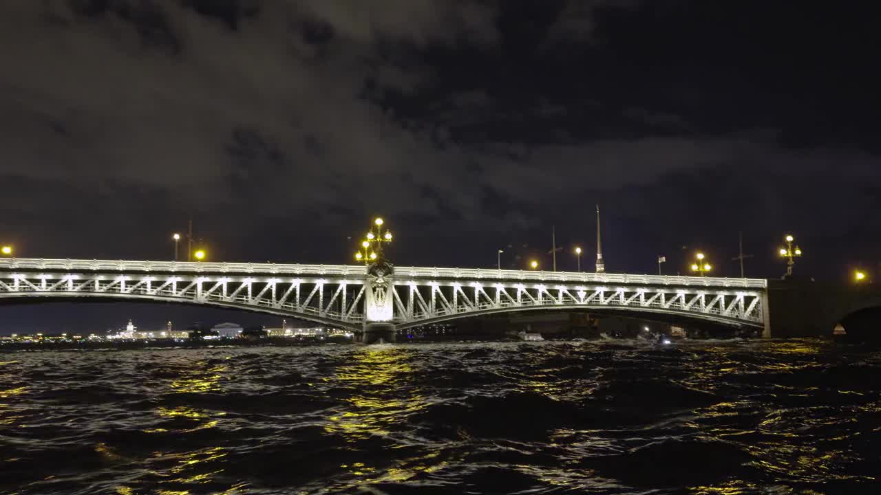 河上一座灯火通明的桥的夜景，下面有船只经过视频下载