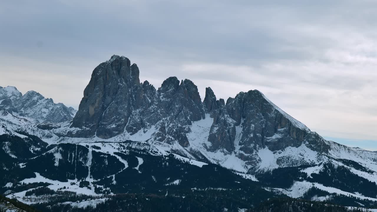 多云的天空下，白雪覆盖的Sasso Lungo (Langkofel)山的壮丽景色，展示了白云石山脉的崎岖之美。视频素材