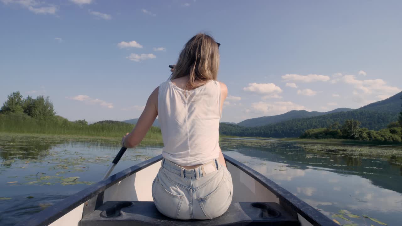 在湖中划独木舟的女人享受着令人惊叹的夏日自然风光视频素材