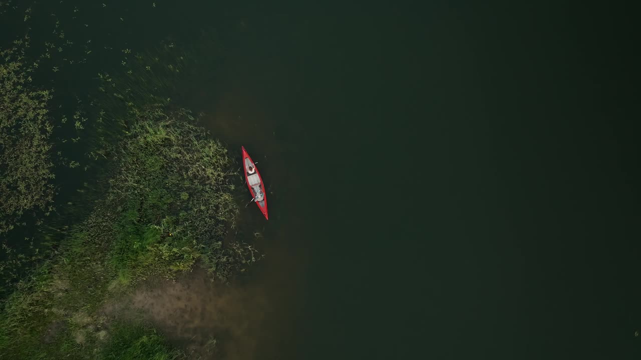 两个人在湖上划独木舟，湖上有一片绿水花园视频素材