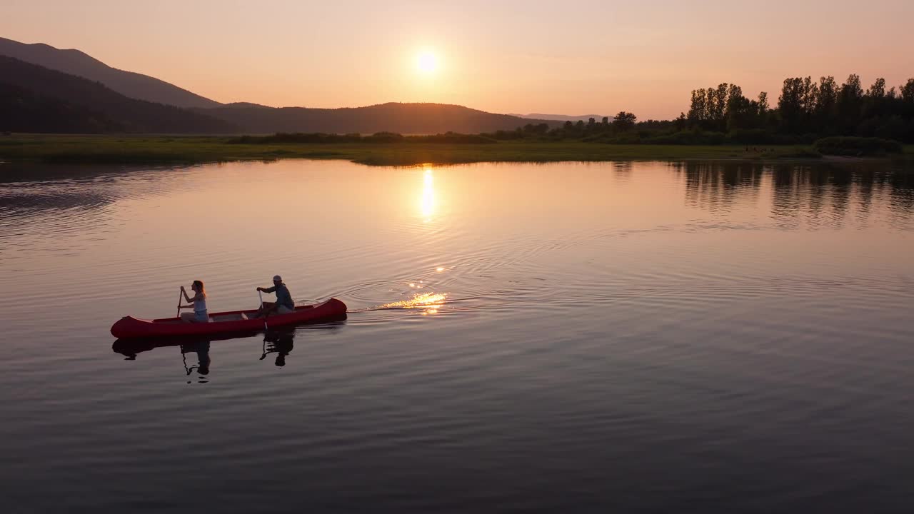 夏日夕阳下，情侣们在湖上划着独木舟享受浪漫的旅行视频素材