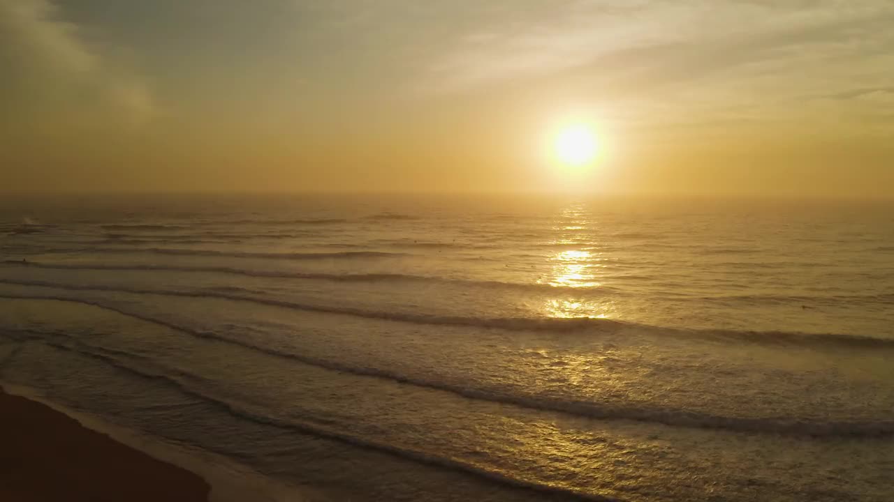 鸟瞰日出地平线上翻滚的海浪。在太平洋多云的天空上，无人机鸟瞰美丽的早晨日出。太阳路径在海面上反射。澳大利亚的风景。视频素材