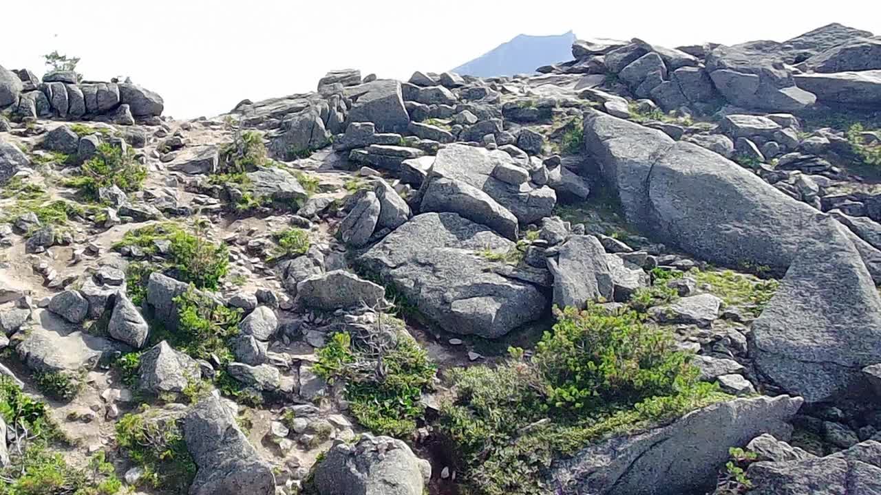 在一个阳光明媚的夏日早晨，无人机在风景如画的山间飞过一个美丽的山口。视频下载