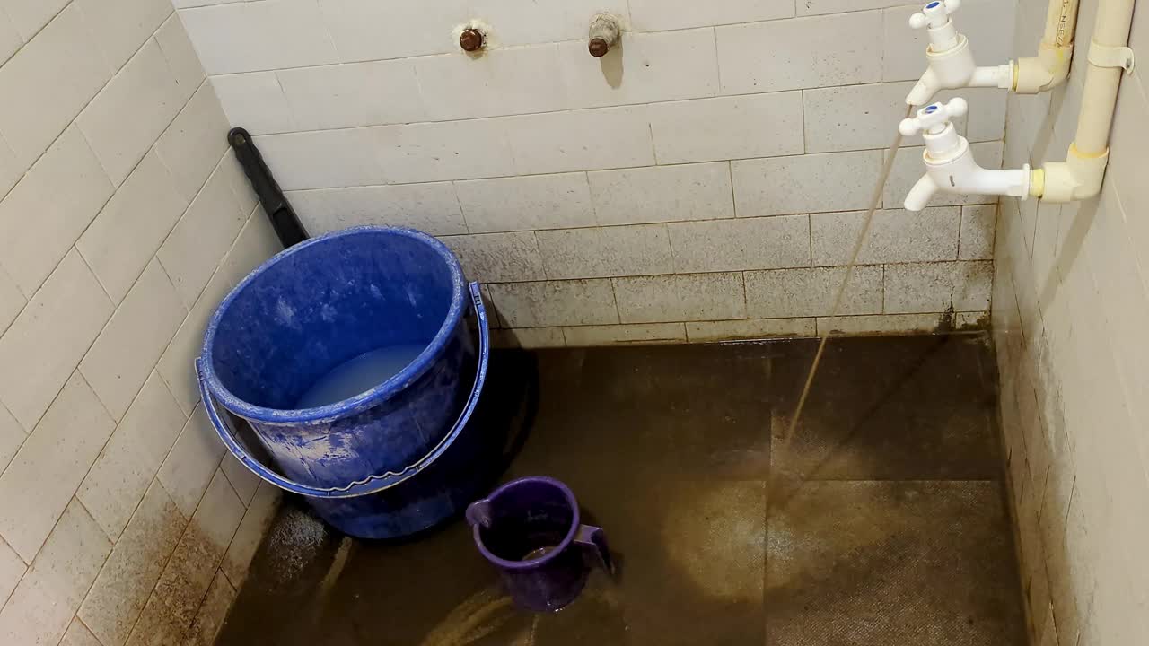 这是一间又旧又脏的公共浴室的特写镜头，地板上漏着泥水视频下载