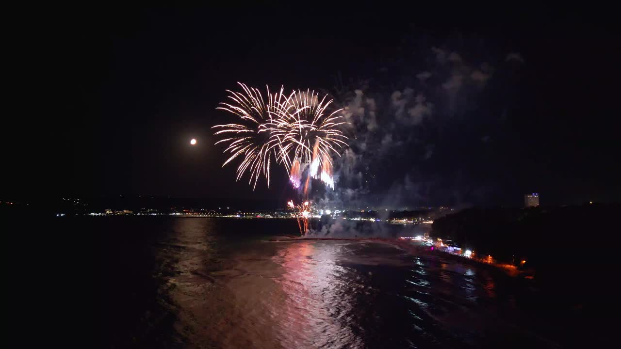 壮观的烟花表演照亮了充满活力的城市滨水区的夜空，倒影在下面的水面上闪闪发光。非常适合庆祝和节日活动视频素材