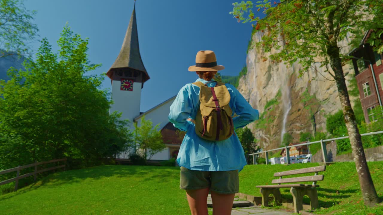 Lauterbrunnen,瑞士。一位年轻的游客背着背包，漫步在阿尔卑斯山上一个有瀑布的著名瑞士村庄的美景中视频素材