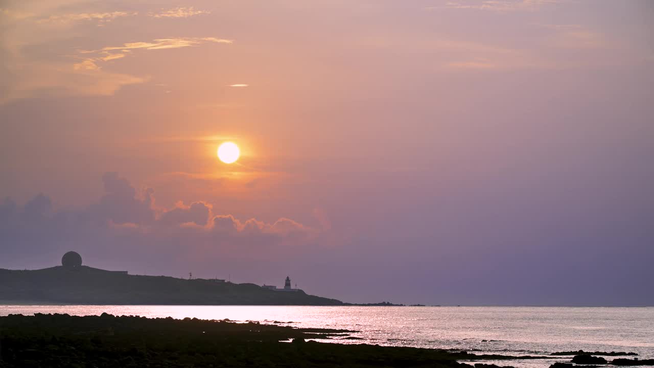 海岸日落与灯塔剪影。视频素材