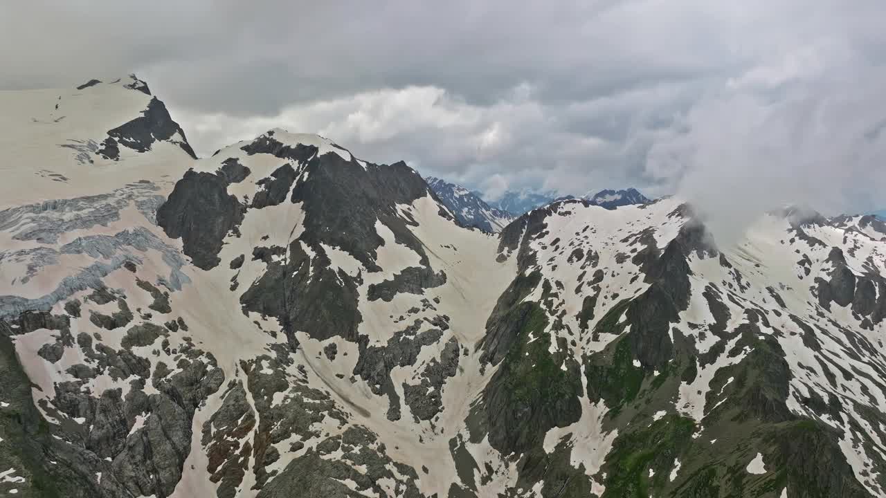 高山间古老的雪冰川。山顶上覆盖着雪。瑞士阿尔卑斯山的多山地形。无人机慢慢飞向山上几乎融化的冰川视频下载