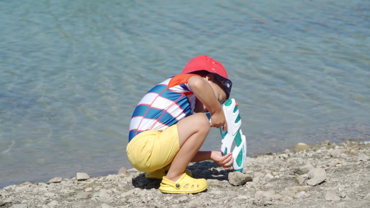 夏日里，穿着防晒服的小孩在湖边玩耍。视频下载