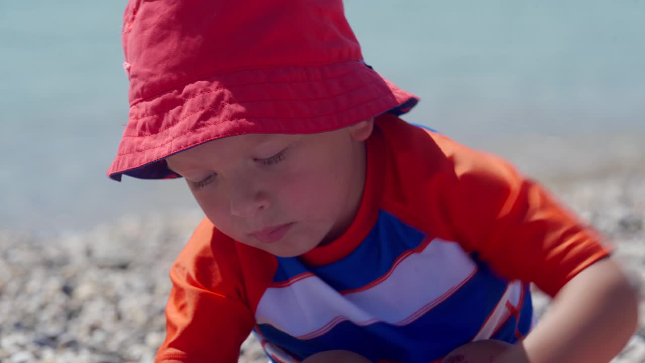 小孩子在沙滩上的充气儿童泳池边玩耍。小男孩穿着防晒衬衫。孩子们暑假。视频素材