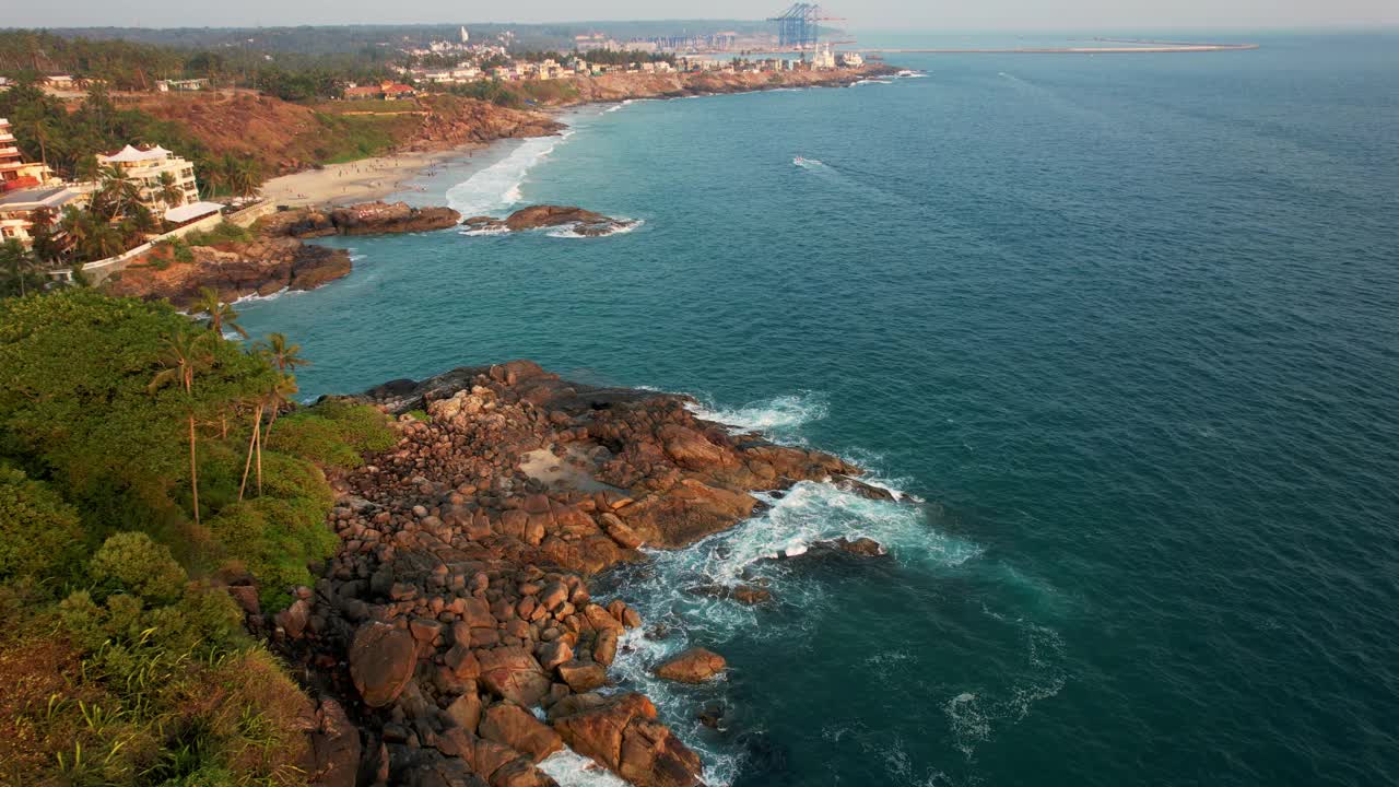 鸟瞰碧绿的海浪撞击岩石海岸线，大海在布满巨石的海岸线周围编织。Kovalam海滩，印度喀拉拉邦。视频下载